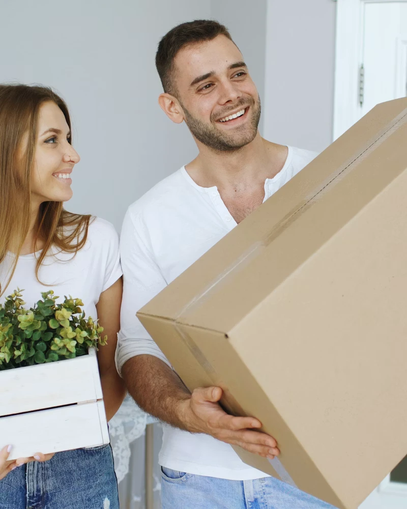 Couple carefully carrying moving boxes into their beautiful new home